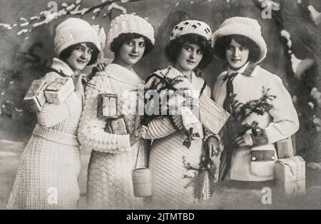 Jeunes femmes avec cadeaux et arbre de noël. Image vintage avec grain et flou de film d'origine Banque D'Images