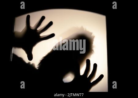 Tableau effrayant des mains derrière le verre, fantôme d'horreur derrière la porte, concept d'Halloween Banque D'Images