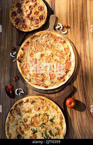 Trois pizzas aux saveurs différentes. Pepperoni, fromage, pomme de terre, oignon, tomate. Pizza italienne de qualité. Banque D'Images