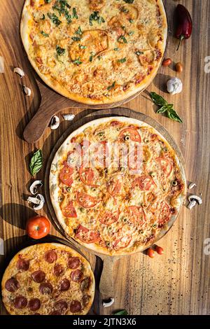 Trois pizzas aux saveurs différentes. Pepperoni, fromage, pomme de terre, oignon, tomate. Pizza italienne de qualité. Banque D'Images