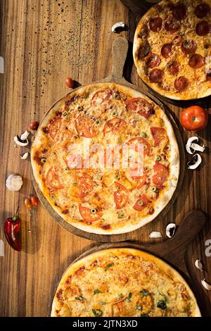 Trois pizzas aux saveurs différentes. Pepperoni, fromage, pomme de terre, oignon, tomate. Pizza italienne de qualité. Banque D'Images