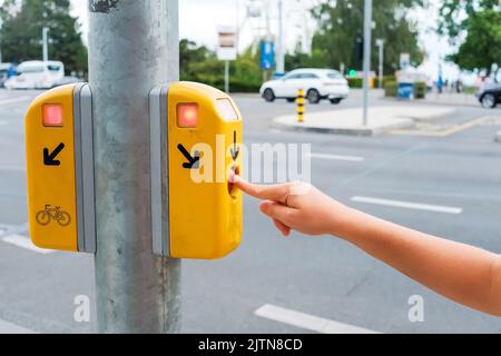 Bouton sur un feu de circulation pour céder la place aux piétons, pressé par la main d'un enfant qui veut traverser la rue, en Europe. Banque D'Images