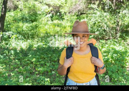 Une femme africaine marche à travers la forêt, regardant la caméra. Banque D'Images