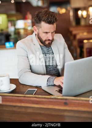 HES a eu un travail à faire : un homme d'affaires moderne utilisant son ordinateur portable dans un café. Banque D'Images