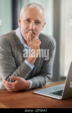 Laissez-moi y réfléchir... Portrait d'un homme d'affaires mûr qui a l'air réfléchi lorsqu'il travaille sur son ordinateur portable au bureau. Banque D'Images