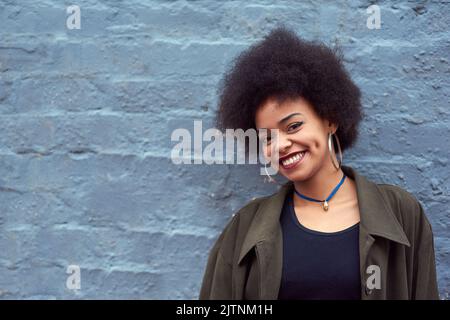 La vie ne devrait pas être plus belle. Portrait d'une jeune femme heureuse debout contre un mur de briques. Banque D'Images