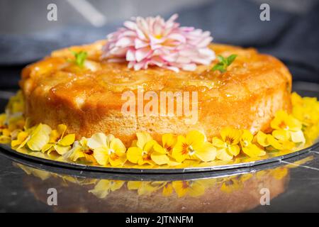 Gâteau à l'ananas maison à l'envers avec menthe et fleurs comestibles décoratives. Banque D'Images