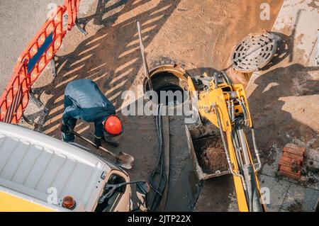 Le travailleur effectue le nettoyage, la réparation et l'entretien des égouts de rue extérieurs. Banque D'Images