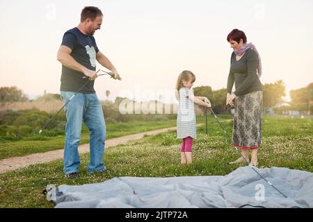 Beaucoup de mains font du travail léger. Une jeune famille qui met une tente ensemble. Banque D'Images