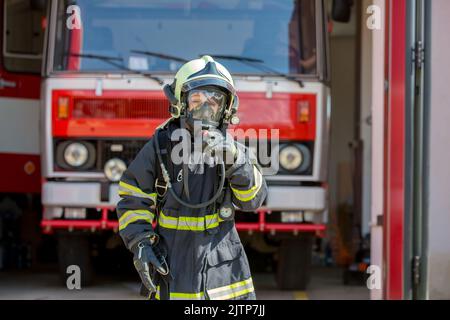 Enfant, mignon garçon, vêtu de gants de pompiers dans une caserne de pompiers avec camion de pompiers, les enfants rêvent Banque D'Images