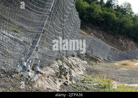 Système de barrière contre les chutes de pierres robuste actif avec treillis métallique le long de la route, frein pour les chutes de pierres. Banque D'Images