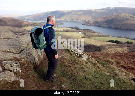 Homme âgé solitaire sur la piste du Yew Crag en direction du lac Ullswater dans le parc national du Lake District, Cumbria, Angleterre, Royaume-Uni Banque D'Images