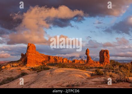 Balanced Rock au coucher du soleil dans le parc national d'Arches près de Moab, Utah. En arrière-plan se trouvent les montagnes de la Sal. Banque D'Images