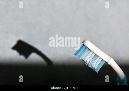 Vieille brosse à dents avec ombre dans une salle de bains. Banque D'Images