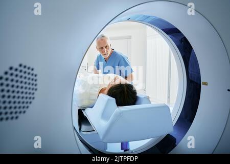 Un technologue en acquisition CT qui domine le patient dans le scanner de tomodensitométrie pendant la préparation de la procédure. Femme entrant dans le scanner CT Banque D'Images