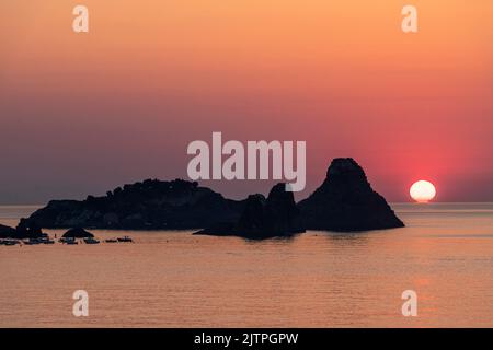 Lever du soleil derrière les Faraglioni ou isole dei Ciclopi (îles cyclopées), un groupe de basalte volcanique s'accumule au large du village d'ACI Trezza, en Sicile Banque D'Images