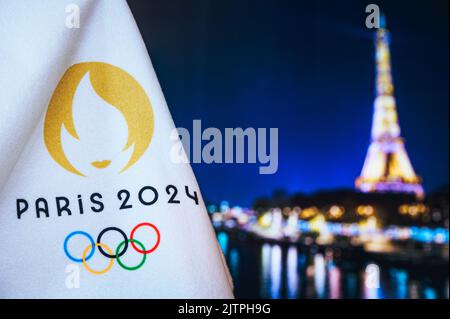 PARIS, FRANCE, AOÛT 8. 2022 : Jeux olympiques de Paris 2024. Logo officiel des jeux sur couverture blanche. Paris sombre dans la nuit en arrière-plan. La Tour Eiffel Banque D'Images