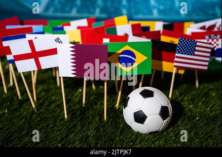 Papier peint football. Ballon de football sur gazon vert et 32 drapeaux qui joueront au Qatar le 2022 décembre Banque D'Images