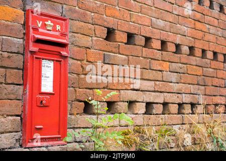 Gros plan de la boîte postale rouge Victoria Regina (toujours utilisée par le bureau de poste/Royal Mail) située dans un vieux mur de briques dans un village rural du Royaume-Uni. Banque D'Images