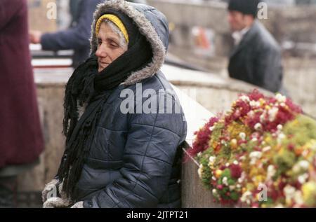 Bucarest, Roumanie, janvier 1990. Quelques semaines après la révolution anticommuniste, une femme âgée reste dehors dans le froid en essayant de vendre des fleurs dans le centre de Bucarest. Banque D'Images