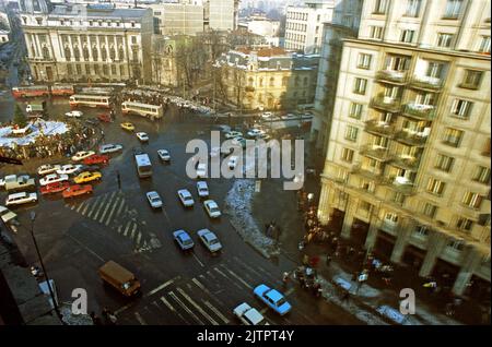 Bucarest, Roumanie, janvier 1990. Vue sur la place Romana, l'un des points clés de la révolution anticommuniste de décembre 1989. Les gens se sont rassemblés tous les jours dans les semaines suivant l'événement, pour déposer des fleurs au mémorial (à gauche), pour allumer des bougies, et prier. Banque D'Images