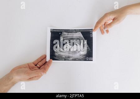 Les parents d'un couple ont un cliché échographique de leur futur bébé dans l'utérus. Concept de l'amour et des soins pendant la grossesse, l'attente et le bébé né. Banque D'Images