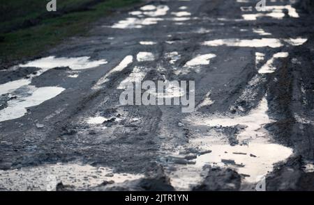 Route de terre après la pluie. Flaques et boue sur la route. Banque D'Images