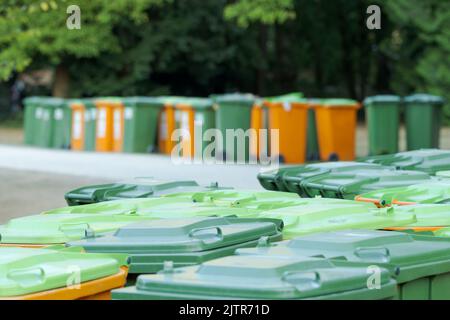 Ensemble de poubelles en plastique vert et orange pour déchets de papier dans un parc public après un festival Banque D'Images