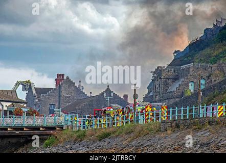 De la fumée s'illumine dans le ciel lorsqu'un incendie majeur a éclaté à la vieille discothèque Cendrillon de Mumbles Pier près de Swansea cet après-midi. Banque D'Images