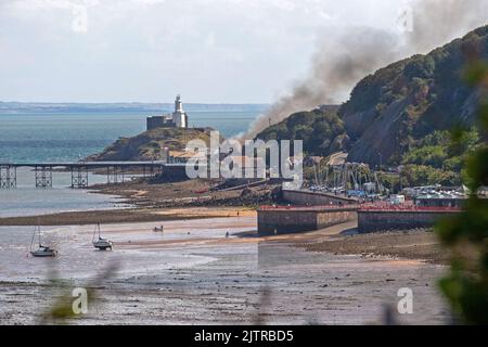 De la fumée s'illumine dans le ciel lorsqu'un incendie majeur a éclaté à la vieille discothèque Cendrillon de Mumbles Pier près de Swansea cet après-midi. Banque D'Images