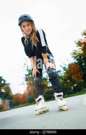 Jeune femme en roller lames appréciant son jour d'automne dans un parc de skate de ville Banque D'Images