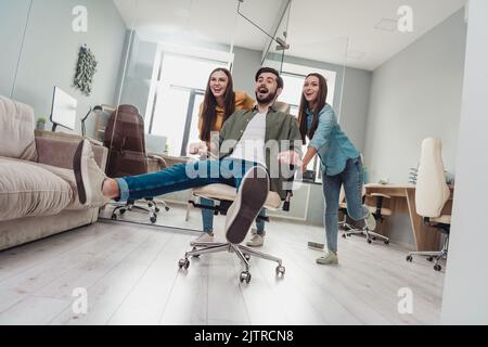 Photo pleine grandeur de trois personnes surjoyées et satisfaites jouant appréciez pause break fauteuil à l'intérieur Banque D'Images