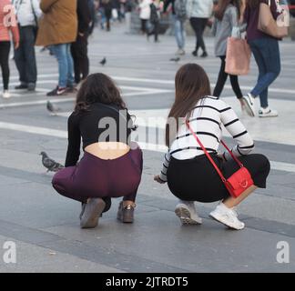 Deux filles nourrissent des pigeons dans la place Banque D'Images