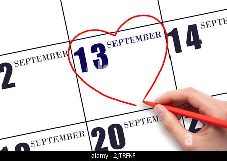 13th jour de septembre. Une main de femme dessinant une forme de coeur rouge à la date du calendrier du 13 septembre . Le coeur comme symbole de l'amour. Mois d'automne. Jour de Banque D'Images