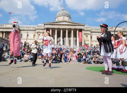 Les gens regardent les danseuses de Morris pendant qu'ils se rassemblent pour les célébrations de la fête de St George à Trafalgar Square, dans le centre de Londres. Banque D'Images