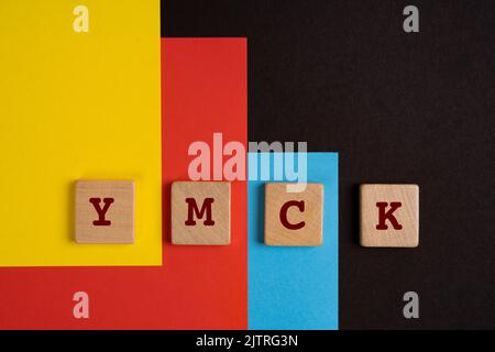 Espace couleur YMCK. Les lettres y, M, C et K sur une serviette en bois sur un fond jaune, rouge, cyan et noir Banque D'Images