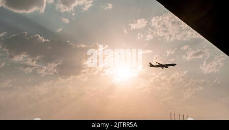 Avion volant dans le ciel avec la toile de fond d'un beau coucher de soleil rose parmi les nuages naturel arrière-plan de l'espace de copie Banque D'Images