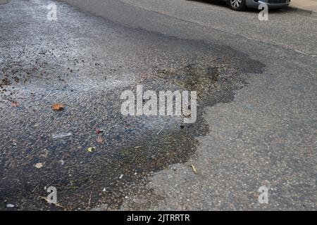 L'eau d'un tuyau souterrain s'échappe par la surface de la route de Broad Street, Boxford, Suffolk, Royaume-Uni Banque D'Images