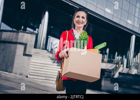Photo d'une dame âgée de marketing tenir le paquet de carton changement de lieu de travail se sentir optimiste occasion à l'extérieur Banque D'Images