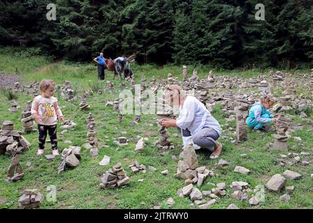 RÉGION DE ZAKARPATTIA, UKRAINE - 29 AOÛT 2022 - Une femme et des enfants empilent la pierre près du lac Synevyr, le plus grand lac de montagne d'Ukraine, comme le Wate Banque D'Images