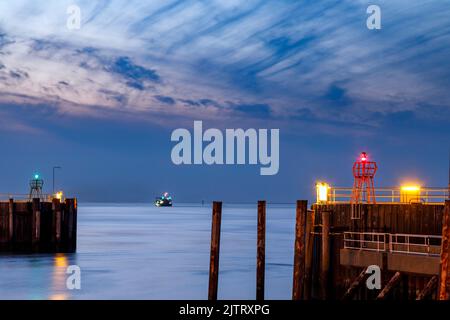 Entrée du port à Cuxhaven à l'embouchure de l'Elbe la nuit, dans le fairway une drague aspirante pendant son travail Banque D'Images