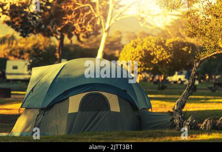 Tente moderne de couleur vert kaki avec couvercle de protection de toit supplémentaire incliné et fixé sur un terrain de camping. Feuillage d'automne en arrière-plan. Camping et Banque D'Images