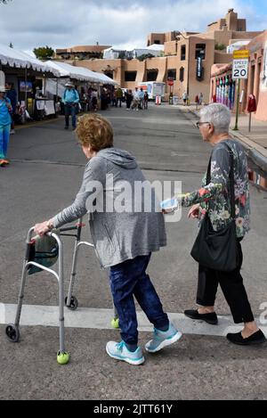 Une femme âgée avec un marcheur est aidée de l'autre côté d'une rue à Santa Fe, Nouveau-Mexique. Banque D'Images