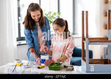 mère et fille mélangeant de la peinture grise à la maison Banque D'Images