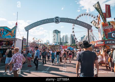 Calgary, Alberta, Canada - 16 juillet 2022 : des foules entrent dans le parc du Stampede, dans la zone de jeux et de manèges à mi-chemin du carnaval Banque D'Images