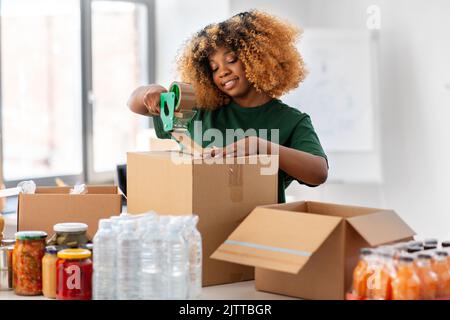 femme volontaire emballant les aliments dans des boîtes de dons Banque D'Images