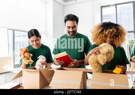 des bénévoles heureux emballant des choses dans des boîtes de dons Banque D'Images