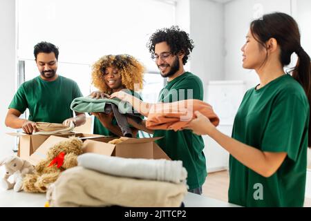des bénévoles heureux emballant des choses dans des boîtes de dons Banque D'Images