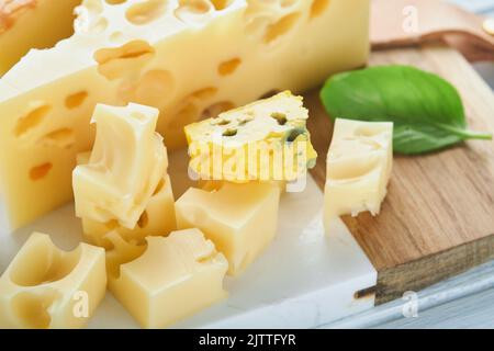 Morceau de maasdam et de camembert, fromage fumé, fromage bleu, parmesan, brie au basilic et poivre sur plateau de marbre blanc vieux bois Banque D'Images