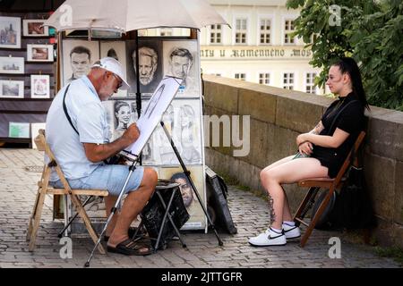 Prague, République Tchèque, 26 juillet: Un artiste de rue peint un portrait d'une touriste féminine sur le pont Charles dans la ville de Prague, sur 26 juillet 2022. Banque D'Images